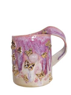 a pink and white mug with gold butterflies on it