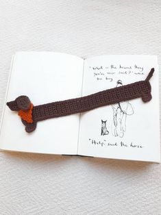 an open book with a crocheted dog on it's cover and ribbon