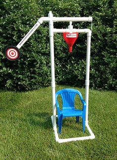 a blue plastic chair sitting in the grass next to a white pole with a target on it