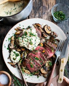 steak, mushrooms and mashed potatoes on a white plate with a serving utensil