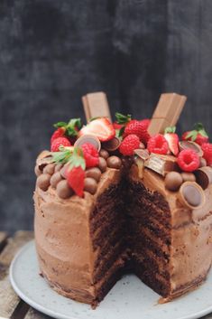 a cake with chocolate frosting and strawberries on top is cut in half to show the inside