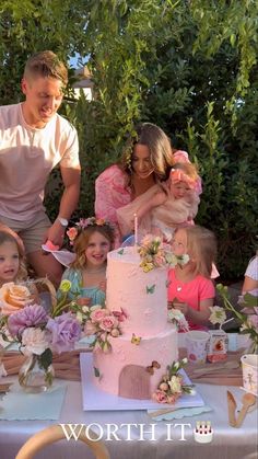 a group of people standing around a cake on top of a table