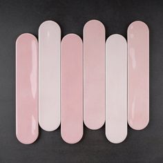 five pink skateboards lined up in a row on a black surface, with one laying down and the other lying down