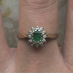 a close up of a person's hand with a ring on their finger and an emerald in the middle