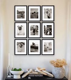 black and white photographs hanging on the wall above a table with a bowl of flowers