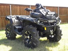 an atv is parked in the grass near a fence