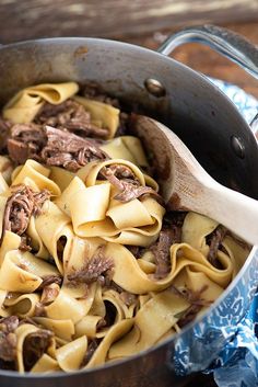 a pot filled with pasta and beef on top of a wooden table