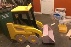 a yellow toy bulldozer sitting on top of a floor next to other toys