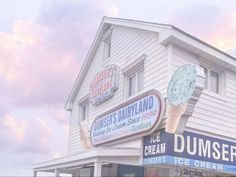 an ice cream shop with signs on the side of it and clouds in the background