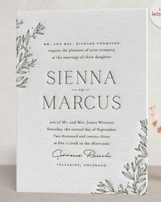 a wedding card with greenery on it