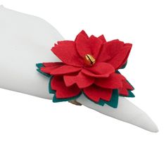 a red flower is on top of a white hand with green leaves and gold centers