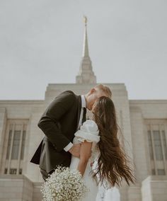 a bride and groom kissing in front of a church