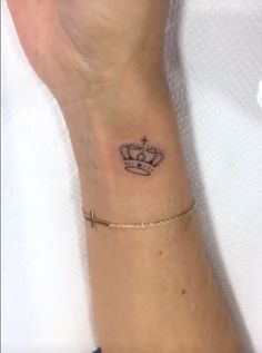 a woman's wrist with a crown tattoo on the left side of her arm