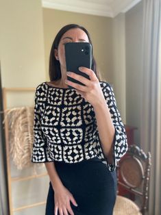 a woman taking a selfie in front of a mirror wearing a black and white top