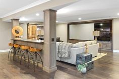 a living room filled with furniture next to a kitchen and dining room table in front of a bar