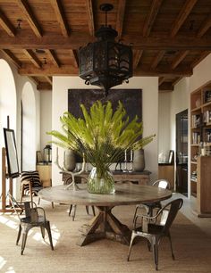 a dining room table with chairs and a plant in the vase on top of it