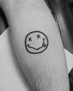 a black and white photo of a person's arm with a smiley face tattoo on it