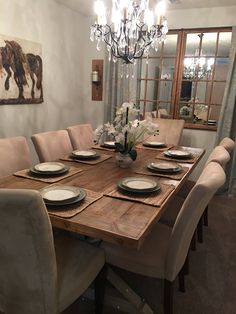 a dining room table is set with place settings for six people and has a chandelier hanging from the ceiling