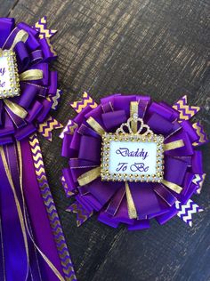 two purple ribbons with gold trim and a tiara on top that says daddy to be