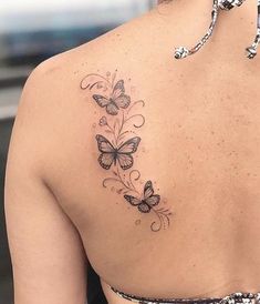 the back of a woman's shoulder with butterfly tattoos on her left arm and chest