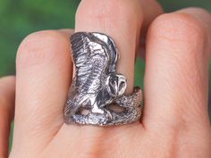 a silver ring with an owl sitting on it's back, in the palm of someone's hand