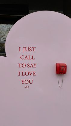 a red phone is attached to a white sign that says, i just call to say i love you