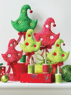 a group of christmas trees sitting on top of a white shelf next to presents and boxes