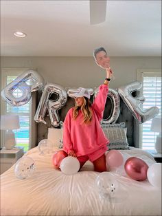 a woman sitting on top of a bed with balloons