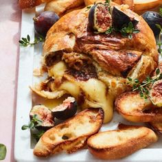 a white plate topped with lots of food on top of a pink table cloth next to bread