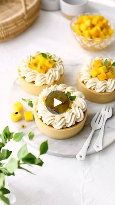 three small desserts on a plate with forks and spoons next to some flowers