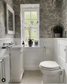 a white toilet sitting under a window next to a sink and radiator in a bathroom