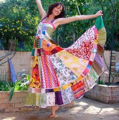 a woman in a colorful dress dancing on a brick patio with her arms outstretched and legs spread out