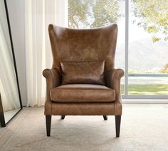 a brown leather chair sitting in front of a window