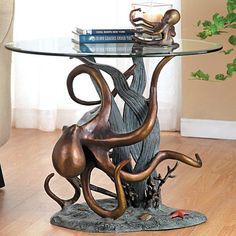 an octopus coffee table with glass top and metal base, on a wooden floor in front of a window