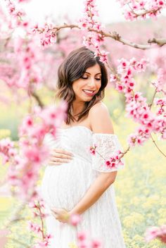 a pregnant woman standing in front of pink flowers