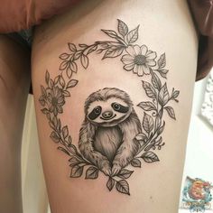 a slotty tattoo on the thigh with leaves and flowers around it