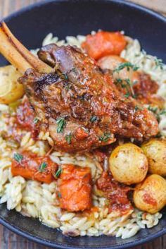 a black bowl filled with rice and meat on top of a wooden table next to potatoes