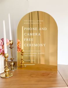 an arch shaped mirror sitting on top of a wooden table next to candles and flowers