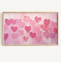 a pink painting with lots of hearts on it in a wooden frame hanging on the wall