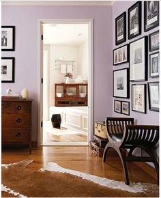 a living room with purple walls and pictures on the wall, including a wooden bench