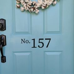 a blue front door with a cotton wreath on it's side and the number 1014