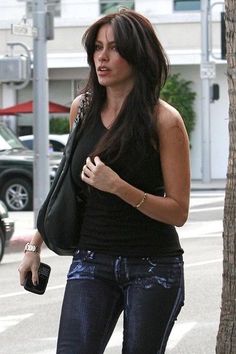 a woman in black shirt and jeans walking down street