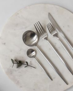 four forks, two spoons and one knife on a marble plate