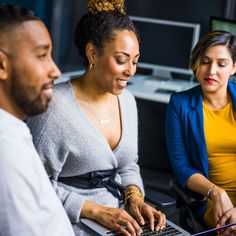 two women and a man looking at a laptop