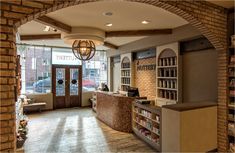 the inside of a coffee shop with brick walls and open shelves on either side of the counter