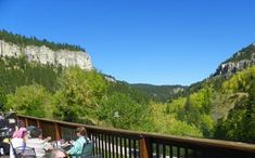 people sitting at tables on a deck overlooking mountains