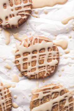 some cookies with icing on top of them sitting on a sheet of wax paper