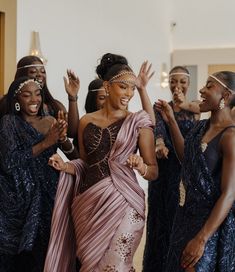 a group of women standing around each other with their arms in the air and one woman wearing a pink dress