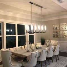 a large dining room table with white chairs and chandelier hanging from the ceiling