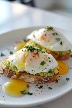 two pieces of toast with an egg and avocado on them sitting on a white plate